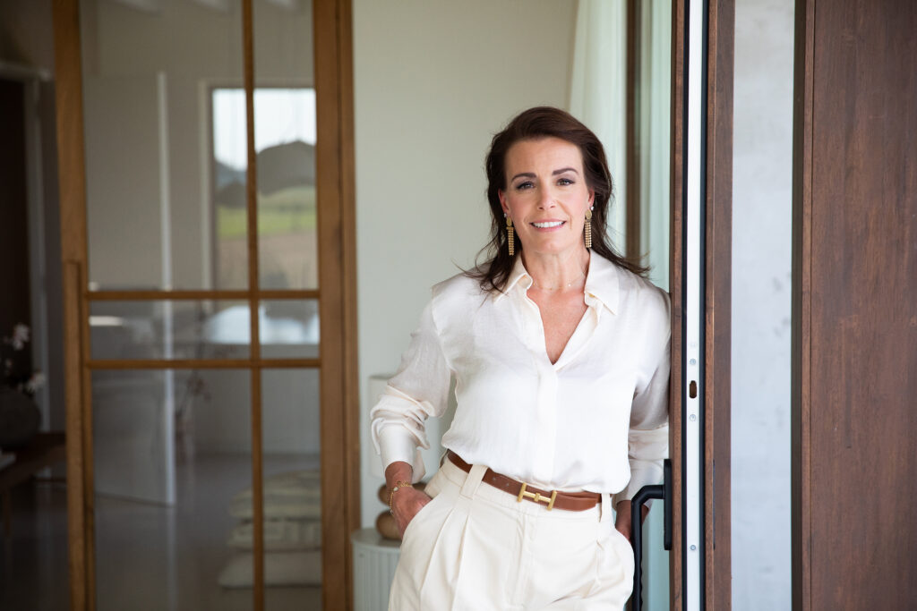 Relatietherapeut Sharon Overweg in een crèmekleurige blouse, leunend tegen een deurkozijn